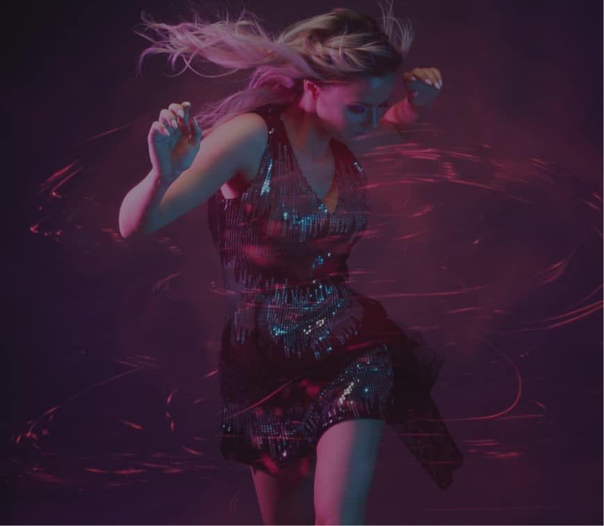 A woman in a dress is dancing with her hair blowing.