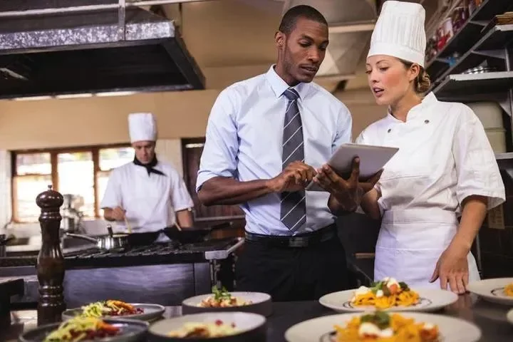 Restaurant Supervisor A man and woman in chef 's hats looking at food.